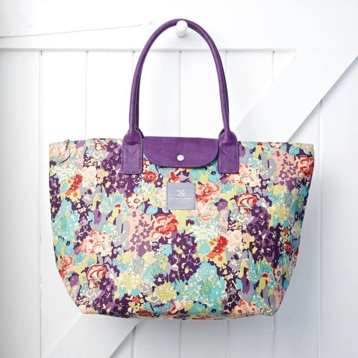 Collier Campbell purple floral bag hanging on white door